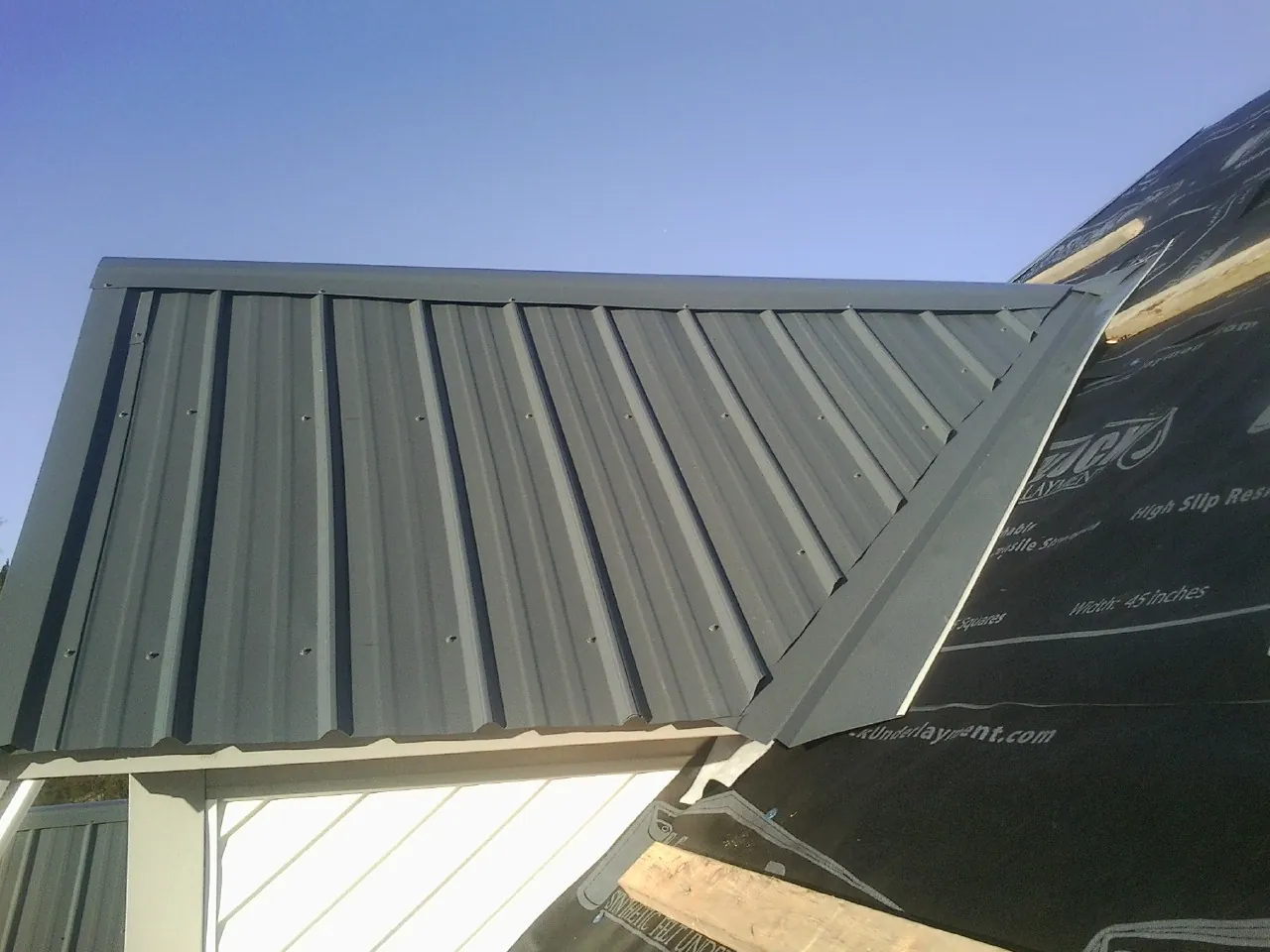Gray metal roof panels going on over a garage gable in Cooksville