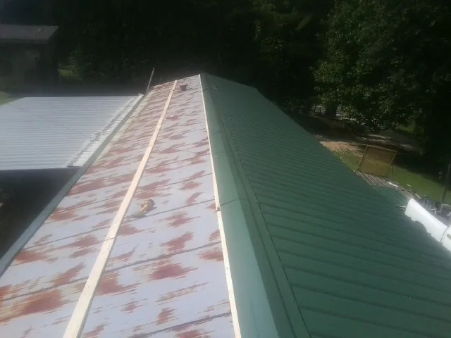 Old rusted panels beside newly installed green metal roofing — Wind Damage Roof Repair by Roofing Brothers in Cooksville