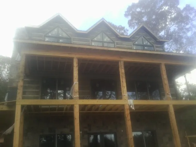 Dormers and porch framing on a large log home under construction — Roof Coating work by our crew in Cooksville