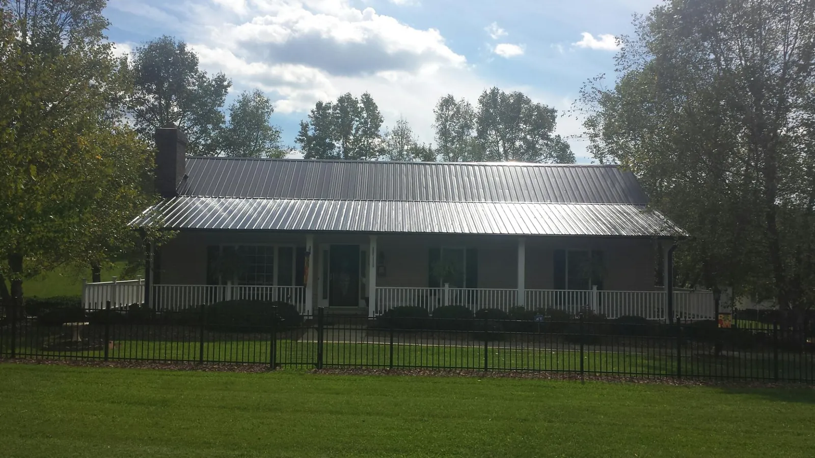Gray metal roof on a brick ranch with a full width front porch — Gutter Guard Installation work by our crew in Cooksville