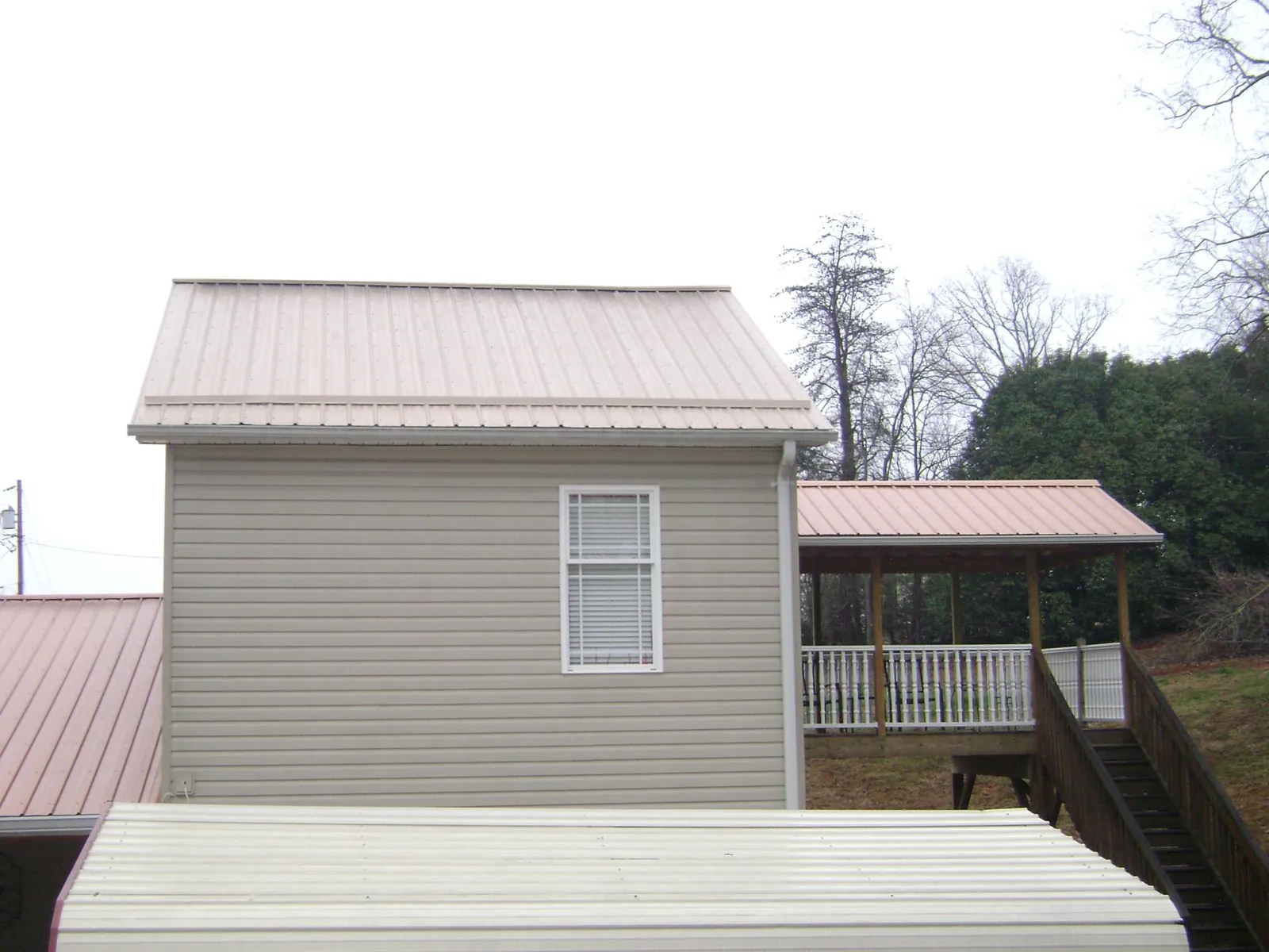 Tan metal roofs on a two story addition and attached porch, from a Roof Replacement job in Cooksville