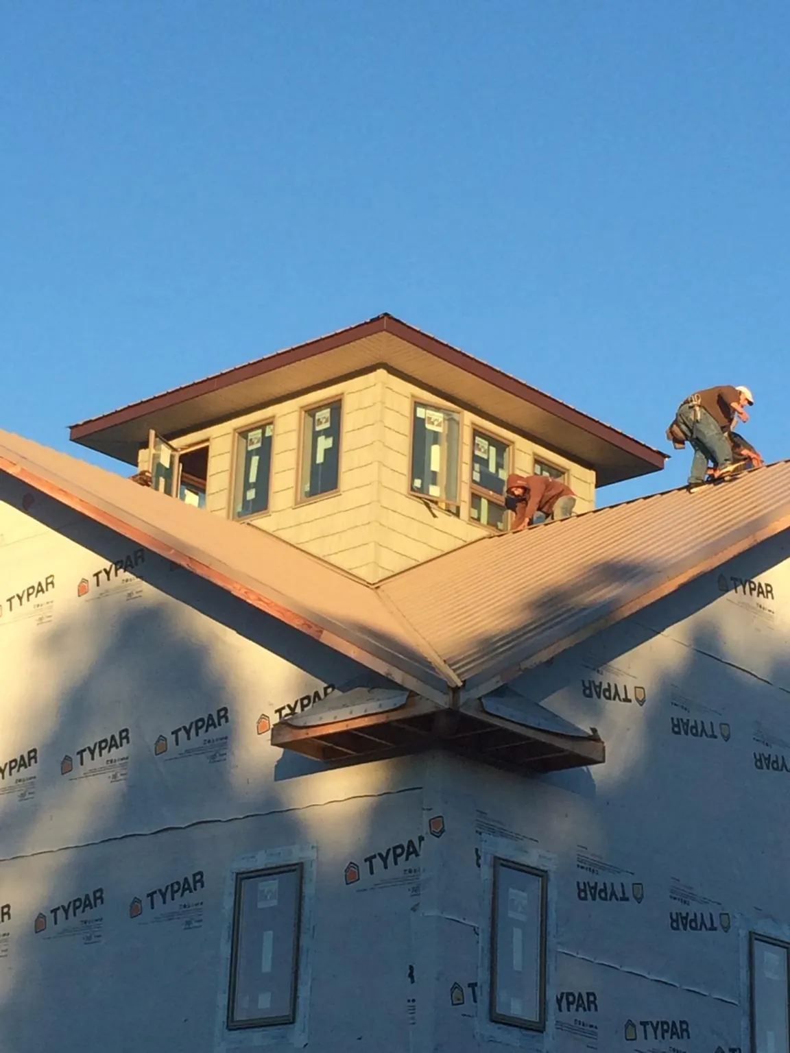Roofers working around a rooftop cupola on a new metal roof at sunset — Roof Waterproofing in Cooksville by Roofing Brothers